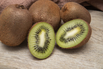 Kiwi on a wooden cutting Board on a light background with a brown waffle towel. Fruits for the house cosmetology. Cooking at home. Quarantine. Kiwi in the section.