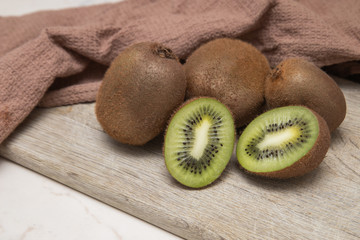 Kiwi on a wooden cutting Board on a light background with a brown waffle towel. Fruits for the home cosmetology. Cooking at home. Quarantine. Kiwi in the section.