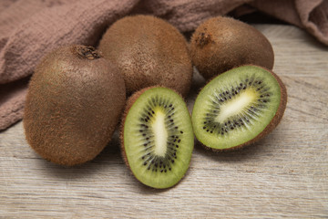 Kiwi on a wooden chopping Board on a light background with a brown waffle towel. Fruit for home cosmetology. Cooking at home. Quarantine. Kiwi in the cut.