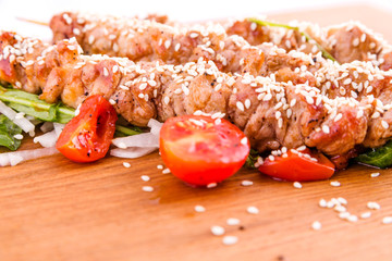 Skewers of pork skewers with daikon and sesame seeds on a wooden board . Horizontal photo. Top view