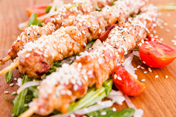 Skewers of pork skewers with daikon and sesame seeds on a wooden board . Horizontal photo. Top view