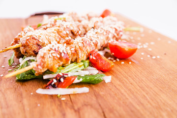 Skewers of pork skewers with daikon and sesame seeds on a wooden board . Horizontal photo. Top view