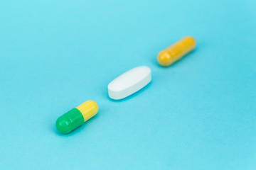 three multi-colored pills lie diagonally on a blue background