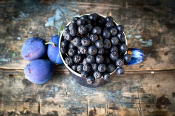 black rowan berries in a mug on a background of an old wooden tabletop