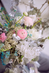 a man in a gray suit and black bow tie holds a bouquet of white hydrangea and pink ranunculus