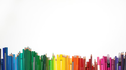 colored pencils and marker in a rainbow row on white background