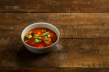 a plate of Italian tomato soup with potatoes and mushrooms on a table of raw boards.