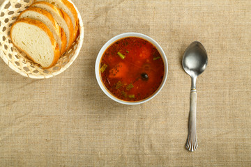 gray plate of italian tomato soup with potatoes and mushrooms linen tablecloth and bread.