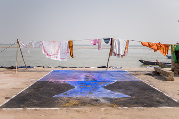 Ropa tendida en Varanasi, Índia, delante del río Ganges. En el suelo un dibujo pintado.