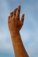 Mano de una chica con tatuajes de henna (mehndi)  y dos anillos dorados. Fondo del cielo azul de Jaisalmer, Índia.
