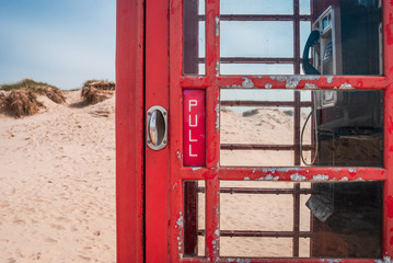 Fototapeta na wymiar Door handle of an old British red telephone box on a sandy beach in Studland, near Sandbanks, Dorset, UK