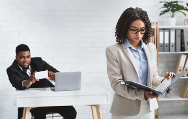 Sexual harassment at workplace. African American guy taking photo of his female colleague in office