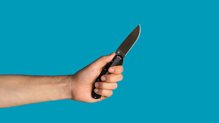 Closeup of young guy holding pocket knife on blue background, blank space. Panorama