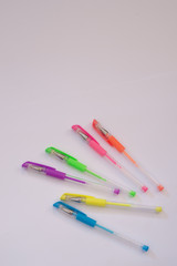 six multi-colored gel pens lie on a white table
