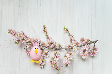 Easter holiday background. Easter egg and sakura twig in bloom on white wooden background. Space for text, top view