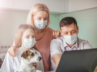 Happy family looking to laptop in mask during the pandemic coronavirus