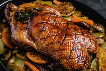 Whole Duck Roasted with Oranges, Carrots and Potatoes on Dark Stone Background