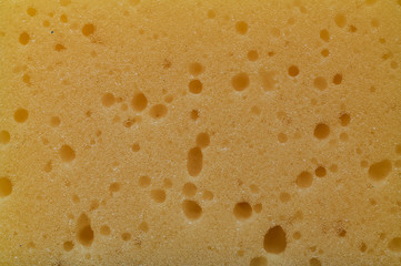 Texture of a yellow foam sponge with holes
