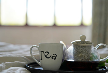 Cup of tea and teapot on the bed. 