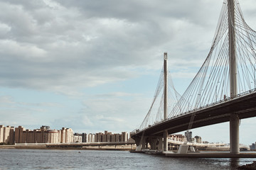 modern cable stayed bridge over the river against cloudy sky. Engineering construction closeup