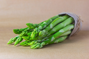 Bunch of fresh asparagus. Selective focus, brown blurred background.