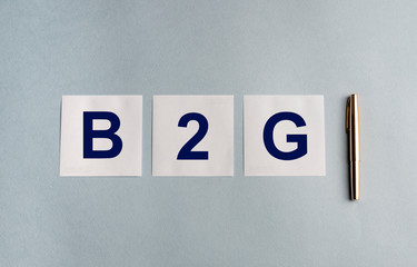 B2G text inscription on white papers with pen on blue table Representing Business 2 Government...