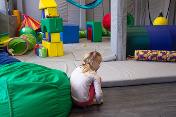 little girl plays in a sensory integration room on floor - obrazy, fototapety, plakaty