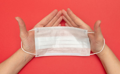medical mask protection against virus and disease in hands closeup on a red background, at home on...