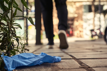 Obraz premium Person wearing black jeans throws a latex glove on the floor. Concept of environment and pandemic. Close up