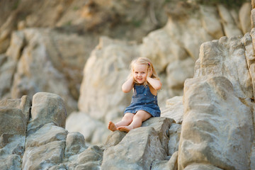 little girl sitting on rock at sunset. travel.