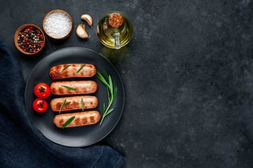 classic grilled sausages with spices in a plate on a stone background with copy space for your text