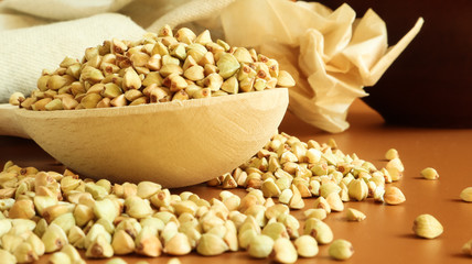 Buckwheat scattered background, raw green cereal in a wooden spoon. Healthy groats. Organic raw non-fried vegetarian food. The concept of a healthy and balanced diet. Diet product. healthy groats.