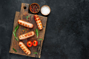 Fototapeta na wymiar classic grilled sausages with spices on a cutting board on a stone background with copy space for your text