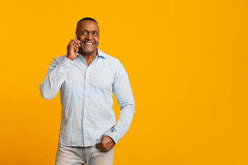 Cheerful middle aged african man with talking on cellphone