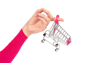 Female hand holds an empty miniature shopping cart on one finger. Close-up shot, isolated on white.
