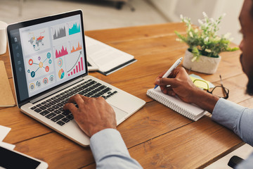 Black entrepreneur analyzing graph on laptop at workplace