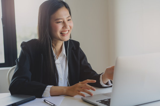 Happy Young Asian Business Woman Waving Hands To Greeting Partner During Making Video Conference With Her Team.