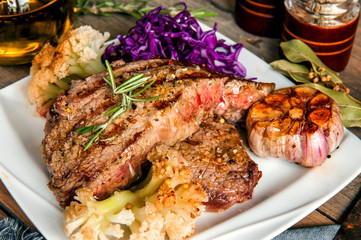 medium beef steak with blood and vegetables on a wooden table