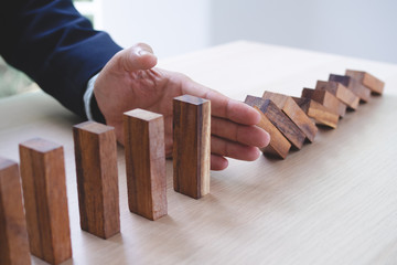 Protection finance from domino effect concept. Hands stop domino effect before destroy stack of...