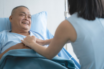 Obraz premium Cheerful asian nurse smiling and talking with elderly patient in the room.