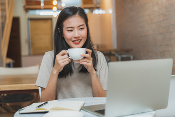 Asian young girl work and studying at home looking online class in laptop computer.