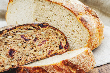 Fresh bread in the assortment of home-made sourdough. Bread with wheat grains and seeds on a wooden Board. Close up