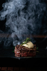 A steaming beef tenderloin steak is grilled in a grill pan with the text copy space. The concept of...