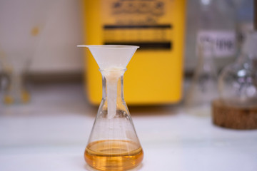 Conical flask with plastic funnel for filtering in advance chemical synthesis in a chemistry laboratory with chemicals