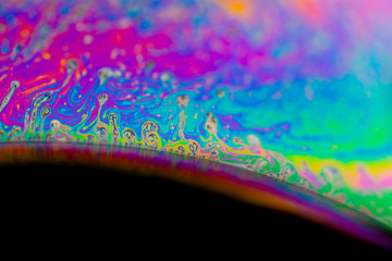 Psychedelic abstract planet from soap bubble, Light refraction on a soap bubble, Macro Close Up in soap bubble. Rainbow colors on a black background. Model of Space or planets universe cosmic galaxy.