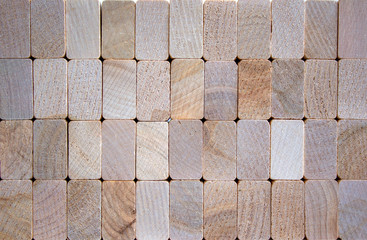 Photo of many small wooden cubes of different heights, tightly lying one after another, imitating the texture of the wall.