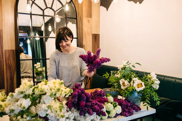Process of making a bouquet of seasonal flowers. Female florist making bouquet in flower shop.