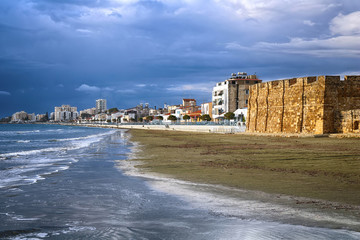 Fototapeta na wymiar Medieval castle, sea shore and embankment in Larnaca, Cyprus. Rainy weather. Beautiful dark blue rain clouds