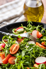 Fresh arugula salad with radishes, tomatoes and red peppers.