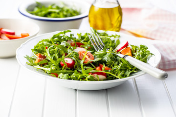 Fresh arugula salad with radishes, tomatoes and red peppers.